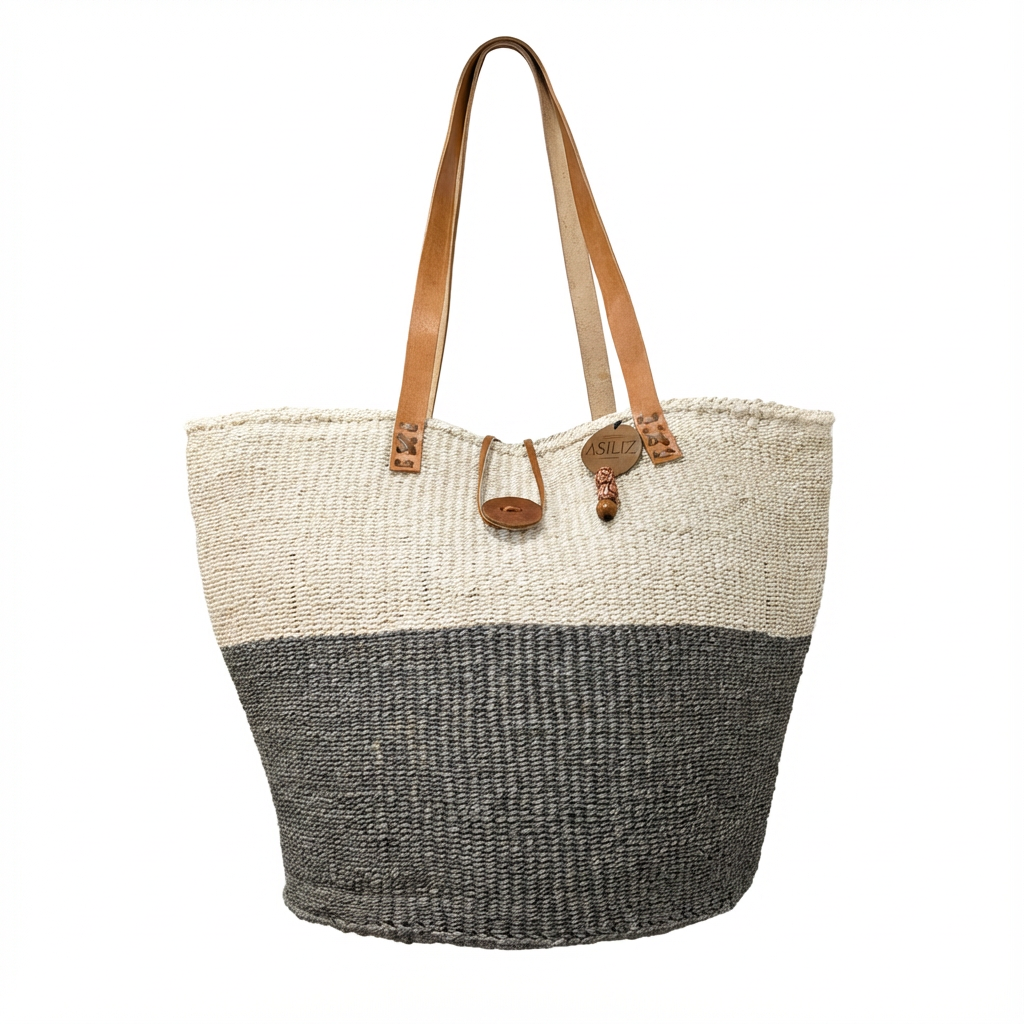 Natural sisal storage basket with leather handles holding blankets in a minimalist living room, handmade by Kenyan artisans by Asiliz.